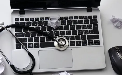 A laptop with a stethoscope on top, symbolizing Web Application Development in the healthcare sector