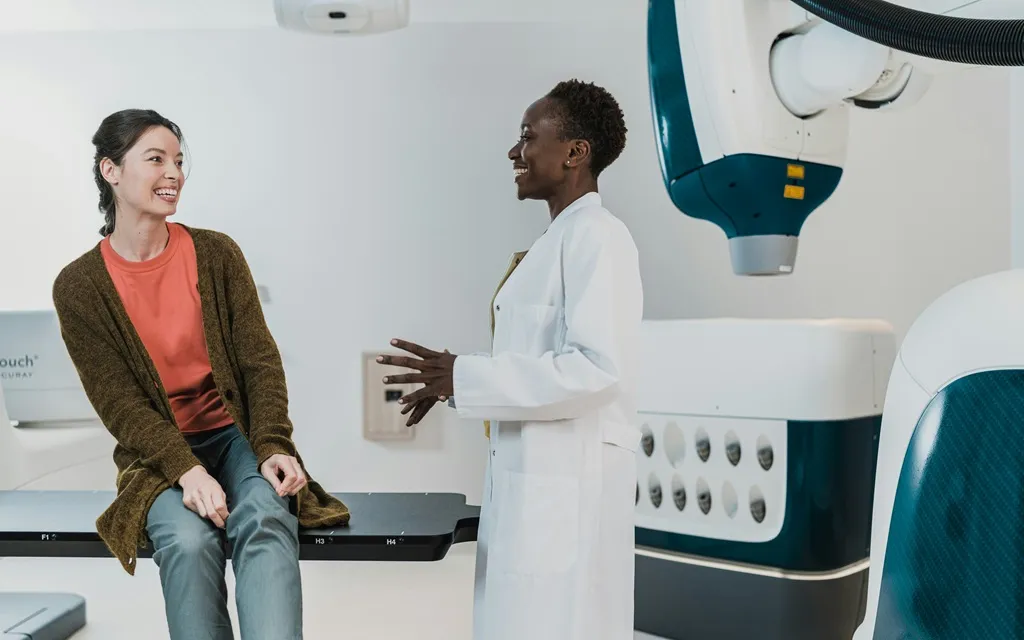 A woman consults with a doctor in a room featuring an x-ray machine.
