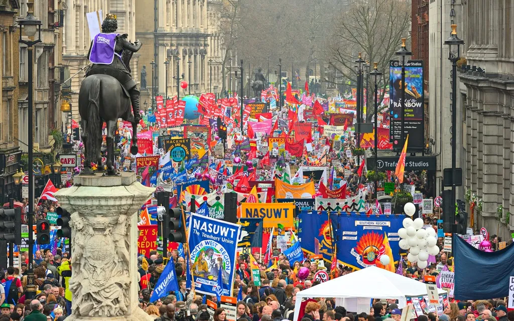 A large crowd of diverse people gathered together in an outdoor setting, engaged in conversation and activities.
